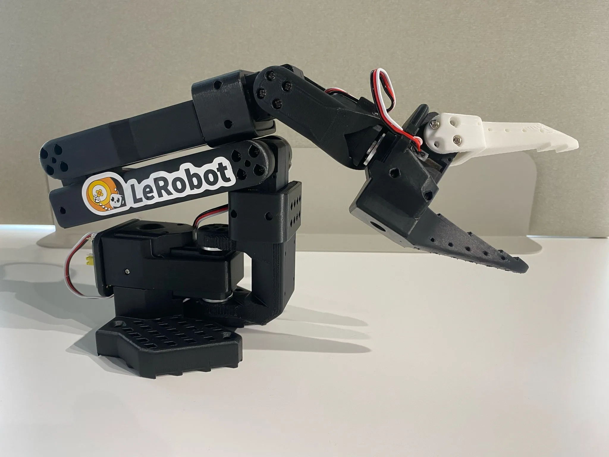 SO-101 follower arm with a printed frame and gripper; upstream project photograph, not an OSR build.